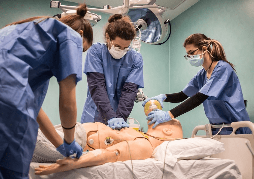 Dei ragazzi iscritti al corso di laurea in infermieristica durante la pratica su un manichino