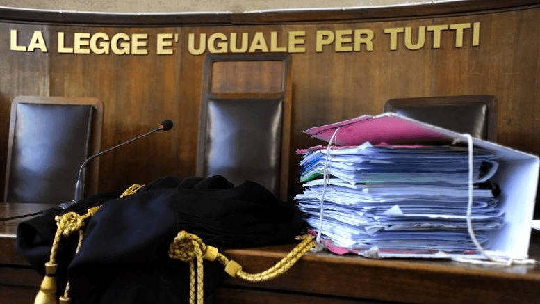 Prescrizione nei processi per morti sul lavoro: una toga accanto a un faldone sui banchi di un tribunale